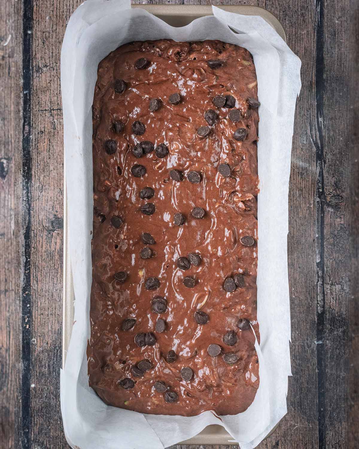 The batter poured into a lined loaf tin and topped with chocolate chips.